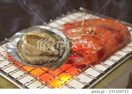 煙り立ち昇る七輪でアワビと海老を焼く 煙り立ち昇る七輪でアワビと海老を焼く 135108753