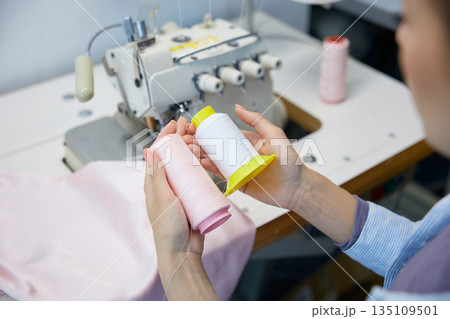 Worker organizes colored threads for garment assembly process Worker organizes colored threads for garment assembly process 135109501