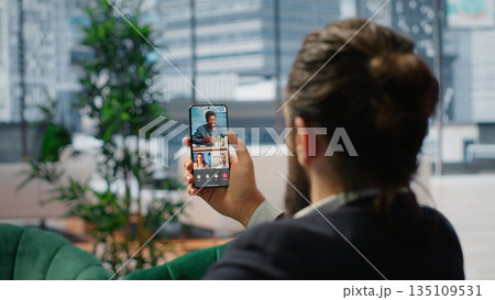 Business director on a phone video call with associates in his office, advisory board meeting to set goals and targets for the future of the company. Male CEO chatting with investors. Camera B. 135109531