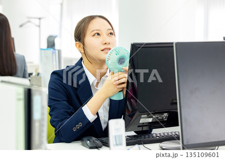 扇風機をオフィスで使う若い女性 扇風機をオフィスで使う若い女性 135109601