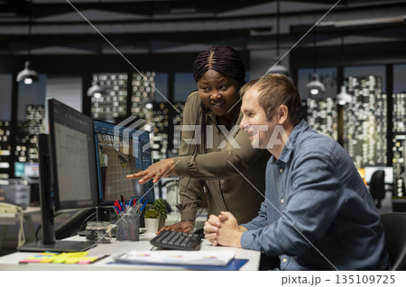 Diverse engineering team designing a floor plan on dual monitors, using computer for interior design customization and rendering. Young man uses digital rendering and remodeling. 135109725