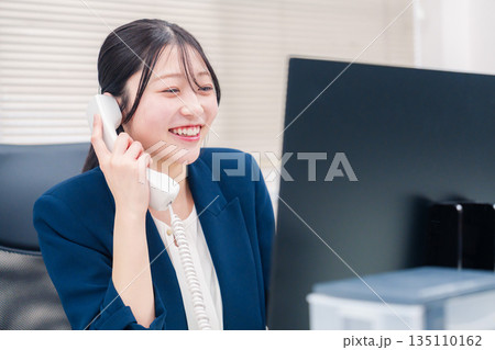 オフィスの固定電話で通話をする女性ビジネスパーソン 135110162