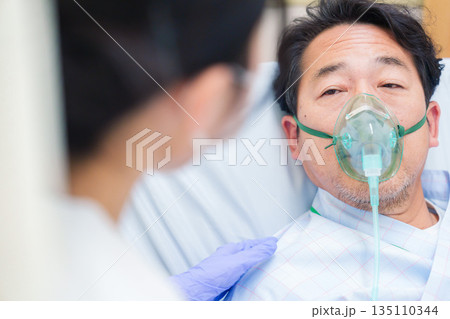 人工呼吸器をつけて話をする入院患者の男性 人工呼吸器をつけて話をする入院患者の男性 135110344