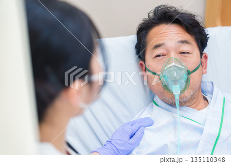 人工呼吸器をつけて話をする入院患者の男性 人工呼吸器をつけて話をする入院患者の男性 135110348
