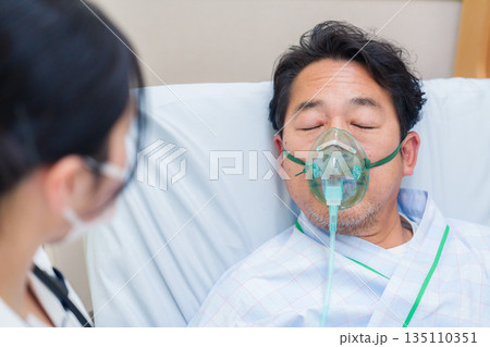 人工呼吸器をつけて話をする入院患者の男性 人工呼吸器をつけて話をする入院患者の男性 135110351
