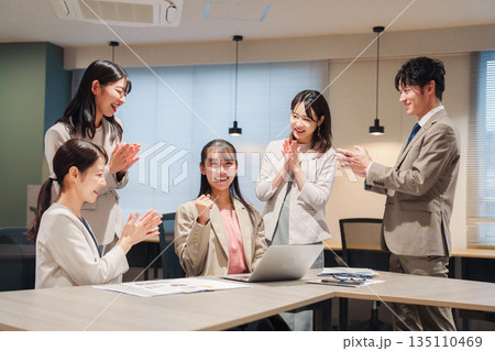オフィスメンバーから拍手喝采される女性社員 135110469