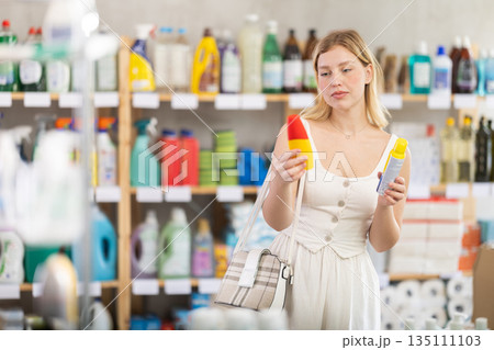 Woman in supermarket choosing insect repellent 135111103