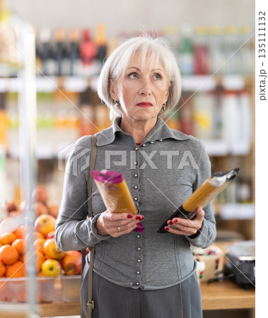 Elderly woman choosing pasta in grocery store 135111132