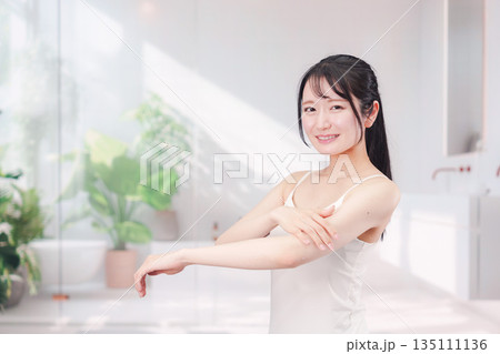 腕にクリームを塗る若い女性 135111136