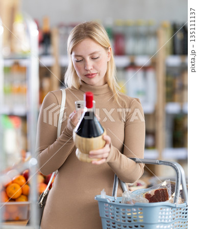 Girl scan QR code, take reading wine label using phone camera in shop Girl scan QR code, take reading wine label using phone camera in shop 135111137