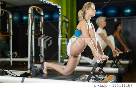 Athletic woman doing leg exercises on reformer 135111167