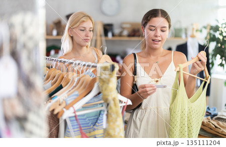 Two young women choosing top in store Two young women choosing top in store 135111204