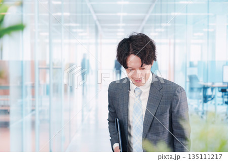 ガラス張りのオフィスの入口でお辞儀をする男性 135111217