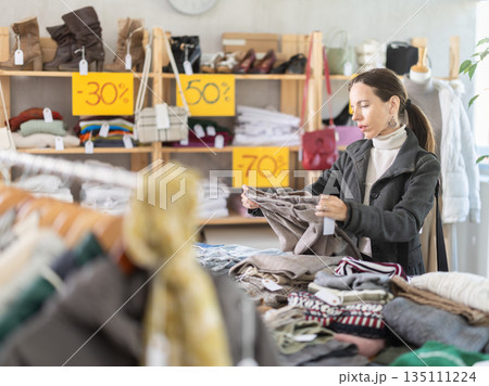 Selective middle-aged woman choosing trousers in clothing store Selective middle-aged woman choosing trousers in clothing store 135111224