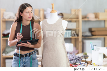 Woman tailor drawing dress design on tablet Woman tailor drawing dress design on tablet 135111235