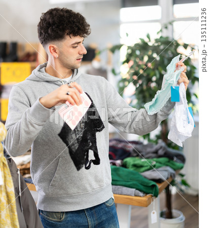 Young man chooses women's panties in clothing store 135111236