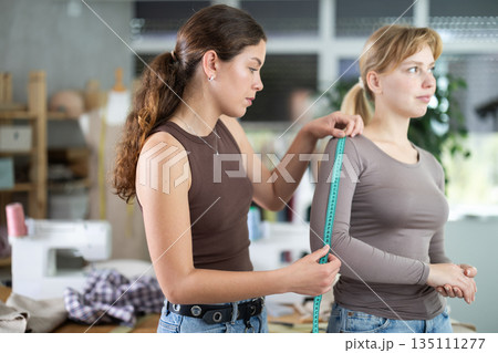 tailor takes measurements from a woman in the workshop tailor takes measurements from a woman in the workshop 135111277