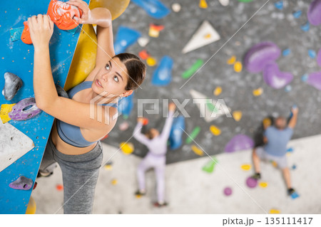 Young girl climbing without ropes and harnesses on bouldering wall Young girl climbing without ropes and harnesses on bouldering wall 135111417