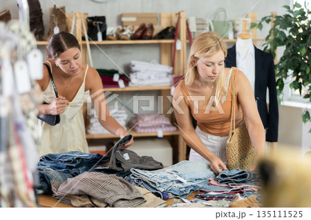 Two young women choosing trousers in store 135111525