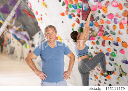 Positive senior coach man on the background of climbing wall Positive senior coach man on the background of climbing wall 135111579