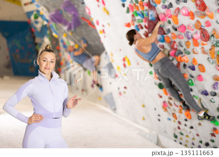 Portrait of slender athletic woman climber on background of climbing wall Portrait of slender athletic woman climber on background of climbing wall 135111663