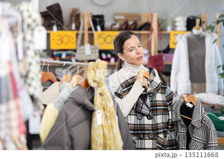Adult woman chooses coat in clothing store 135111668