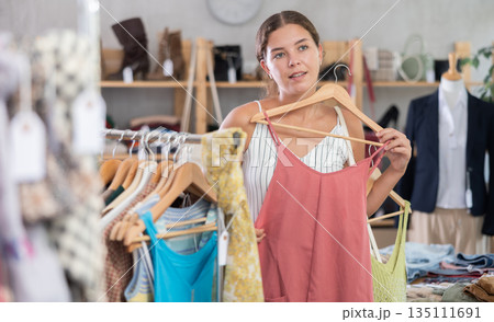 Fashionista girl near showcase examine goods, buying something clothing for summer. 135111691