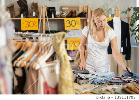 Fashionista girl near showcase examine goods, buying shorts or trousers 135111705