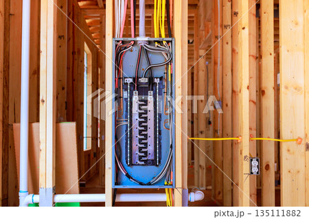 Workers have installed an electrical panel in beams framework of house being built at residential neighborhood. 135111882