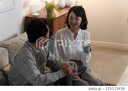 マグカップで飲み物を飲むミドル夫婦　ライフスタイルイメージ 135113436