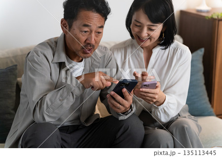 スマートフォンで調べものをするミドル夫婦　ライフスタイルイメージ 135113445