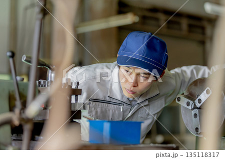 工場で機械を操作する男性作業員 135118317