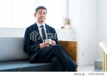 ホテルのソファでコーヒーを飲みながら寛ぐビジネスマン ホテルのソファでコーヒーを飲みながら寛ぐビジネスマン 135118410