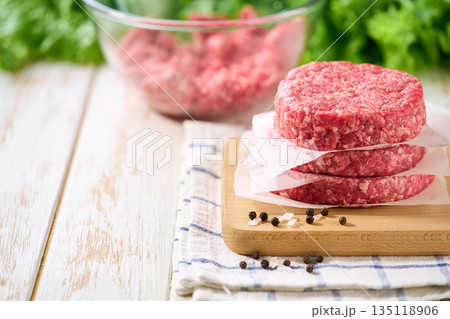 Stack of raw burger beef patties on a white table, selective focus. Natural meat product. Stack of raw burger beef patties on a white table, selective focus. Natural meat product. 135118906