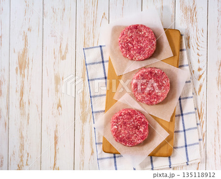 Raw burger beef patties on a white table, top view. Raw burger beef patties on a white table, top view. 135118912