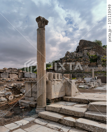 Ancient Ephesus ruins with a Corinthian column and historical stone architecture under a cloudy sky, Selcuk, Turkey. Ancient Ephesus ruins with a Corinthian column and historical stone architecture under a cloudy sky, Selcuk, Turkey. 135119349