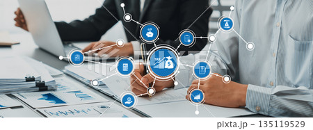 Business professionals analyzing tax data with digital icons on desk representing financial concepts and transactions in modern office environment. Amity Business professionals analyzing tax data with digital icons on desk representing financial concepts and transactions in modern office environment. Amity 135119529