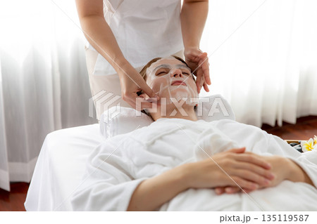 Woman customer indulges in rejuvenating with facial skincare mask. Quiescent Woman customer indulges in rejuvenating with facial skincare mask. Quiescent 135119587