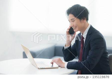 スマホで通話する若いビジネスマン スマホで通話する若いビジネスマン 135119870