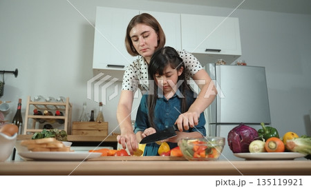 Smart mother and asian girl cooking together and chopping vegetable. Pedagogy. Smart mother and asian girl cooking together and chopping vegetable. Pedagogy. 135119921