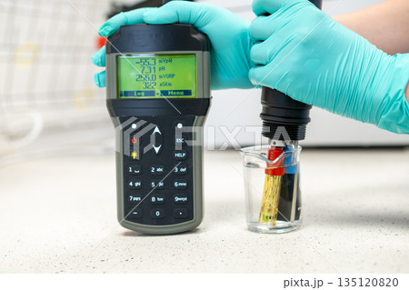 Woman hand in glove measuring pH of water. Woman hand in glove measuring pH of water. 135120820