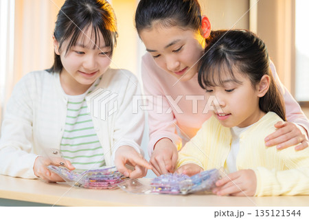 放課後に小学生の女の子がシール帳を使ってシール交換を楽しむ様子 135121544