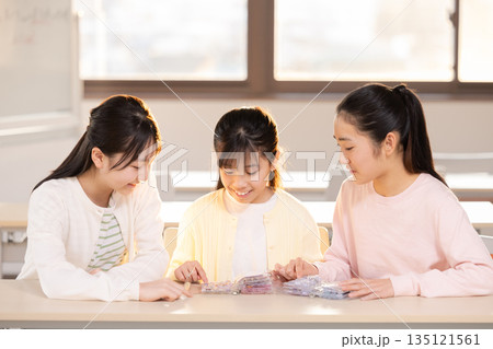 放課後に小学生の女の子がシール帳を使ってシール交換を楽しむ様子 放課後に小学生の女の子がシール帳を使ってシール交換を楽しむ様子 135121561