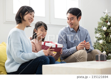 両親からクリスマスプレゼントをもらって喜ぶ小学生の女の子 135121694