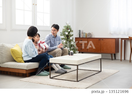 両親からクリスマスプレゼントをもらって喜ぶ小学生の女の子 135121696
