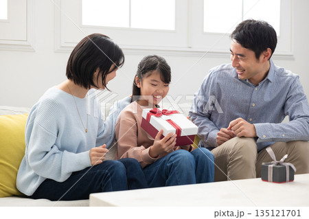 両親からクリスマスプレゼントをもらって喜ぶ小学生の女の子 135121701