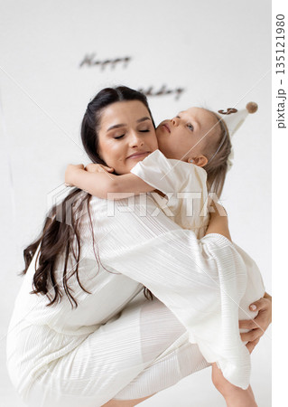 A tender moment between a mother and her daughter, filled with love and affection, captured in a soft, natural light setting. A tender moment between a mother and her daughter, filled with love and affection, captured in a soft, natural light setting. 135121980