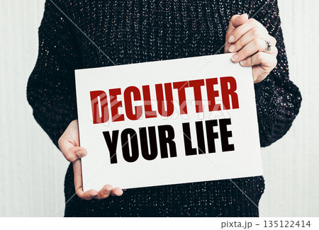 Girl holding a card with text DECLUTTER YOUR LIFE. Girl holding a card with text DECLUTTER YOUR LIFE. 135122414
