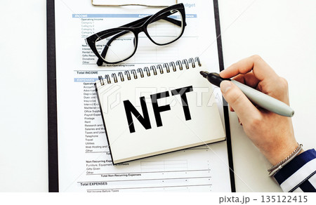 NFT text, written on a note book with eyeglasses 135122415