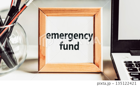 "Emergency fund" text in a wooden frame on an office table. Financial concept. 135122421